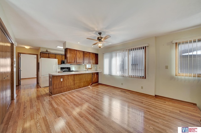 4932 High St, Lincoln, NE 68506 - kitchen with freestanding refrigerator, brown cabinetry, a peninsula, and plenty of natural light