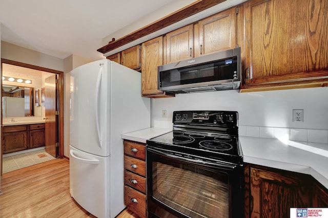 4932 High St, Lincoln, NE 68506 - kitchen with black electric range, stainless steel microwave, light countertops, freestanding refrigerator, and light wood-style flooring