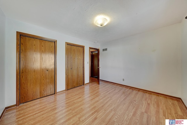 4932 High St, Lincoln, NE 68506 - unfurnished bedroom featuring two closets, light wood finished floors, and baseboards