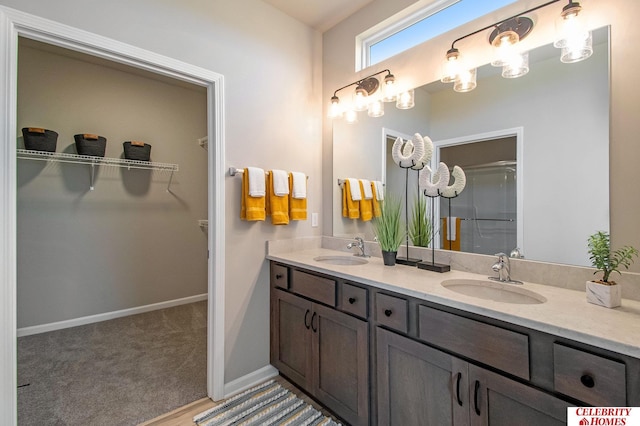 full bathroom featuring double vanity, a shower with door, baseboards, and a spacious closet