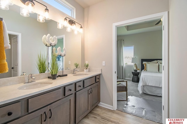 bathroom featuring plenty of natural light, double vanity, wood finished floors, and baseboards