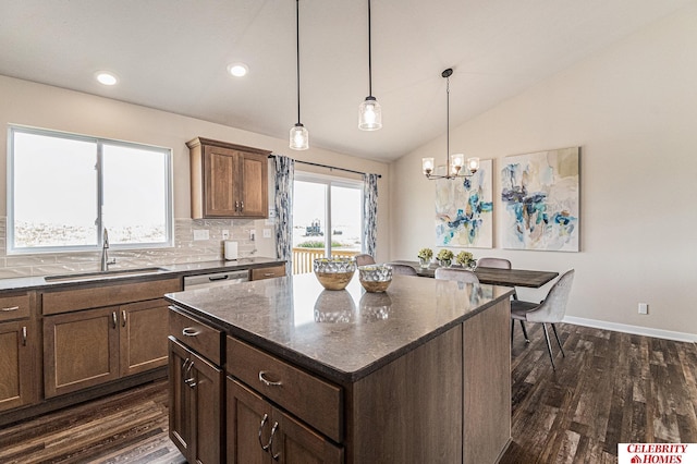 kitchen featuring a sink, vaulted ceiling, dark wood finished floors, a chandelier, and a kitchen island