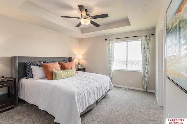 carpeted bedroom with a tray ceiling, baseboards, and ceiling fan