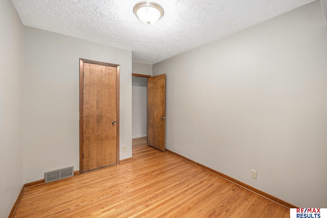 2137 S 49th St, Omaha, NE 68106 - unfurnished bedroom featuring a textured ceiling, light wood-style floors, baseboards, and a closet