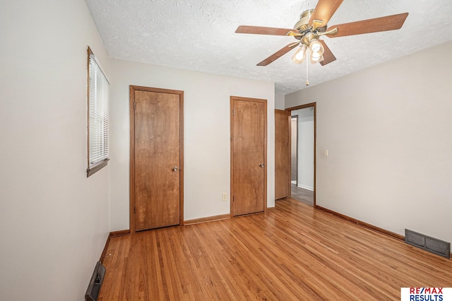 2137 S 49th St, Omaha, NE 68106 - unfurnished bedroom featuring light wood-style flooring, two closets, baseboards, a textured ceiling, and ceiling fan