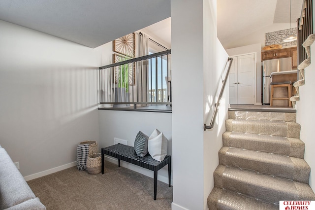 staircase with vaulted ceiling, carpet floors, and baseboards
