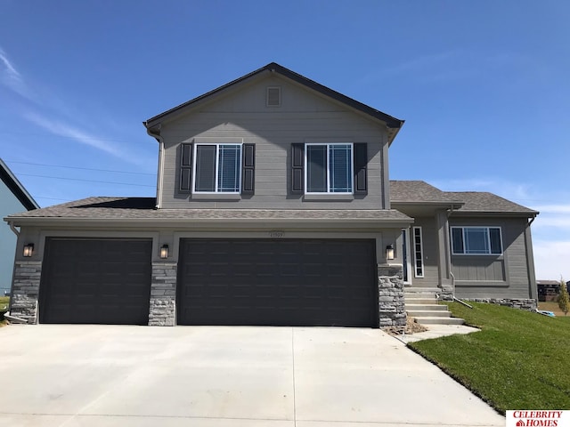 view of front of home with an attached garage, concrete driveway, a front yard, roof with shingles, and stone siding
