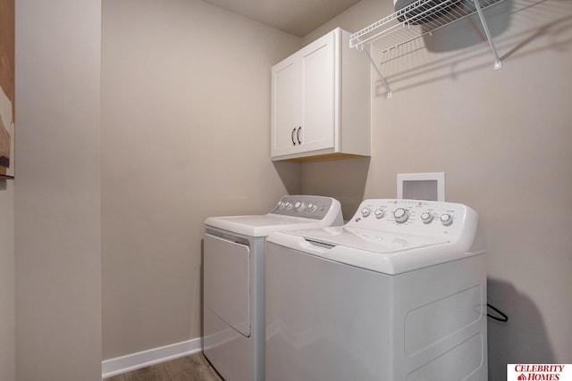 washroom featuring washer and dryer, cabinet space, wood finished floors, and baseboards