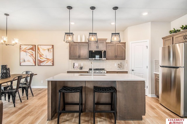 5605 N 181st St, Elkhorn, NE 68022 - kitchen featuring appliances with stainless steel finishes, light countertops, decorative backsplash, light wood-type flooring, and hanging light fixtures