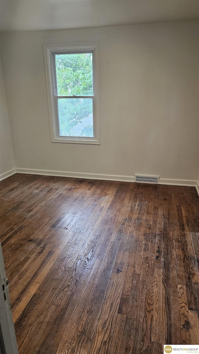 spare room with dark wood-type flooring and baseboards