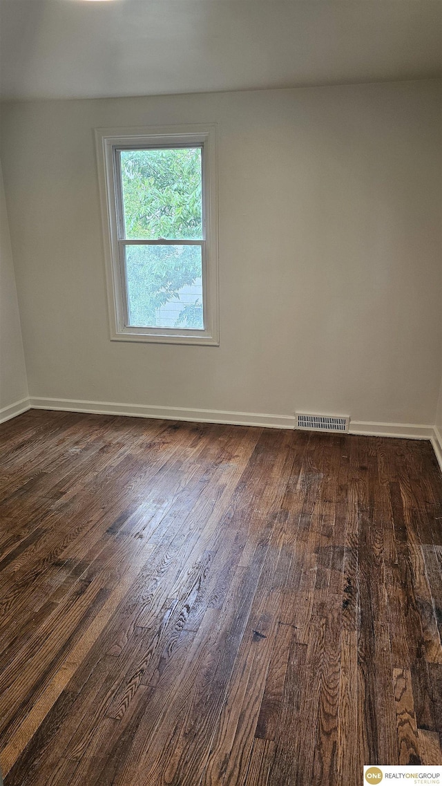 spare room featuring dark wood-style flooring and baseboards
