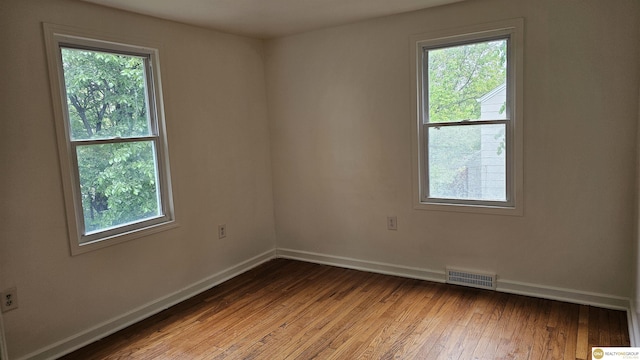 unfurnished room with healthy amount of natural light, baseboards, and hardwood / wood-style floors