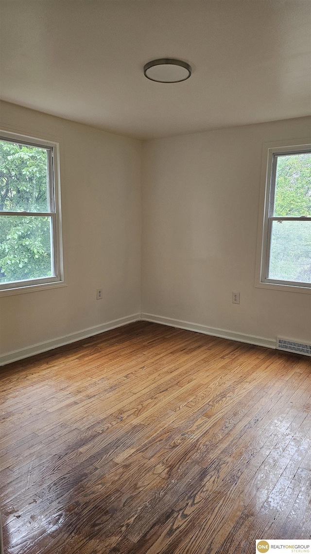 unfurnished room with hardwood / wood-style floors, healthy amount of natural light, and baseboards