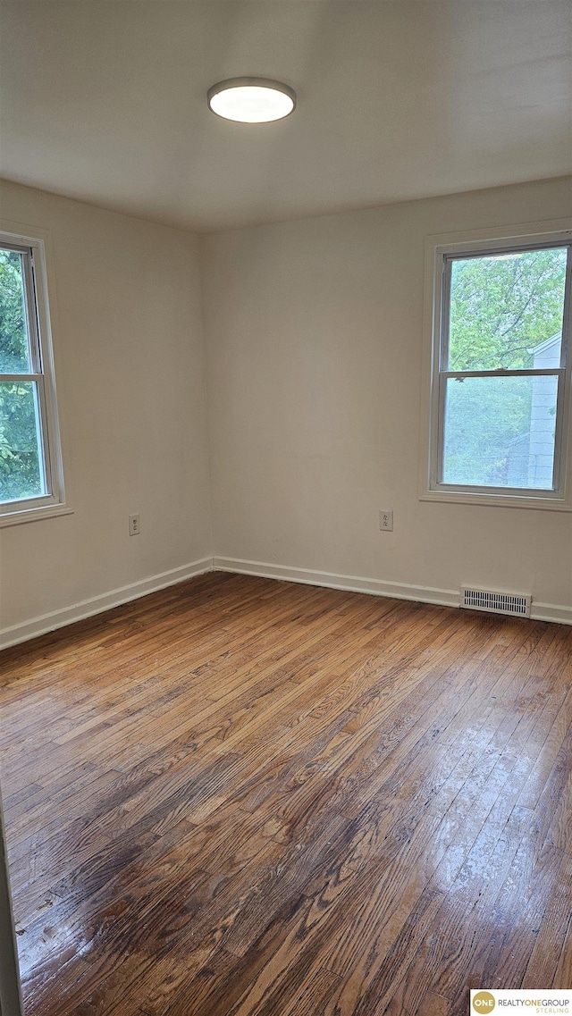 unfurnished room with dark wood finished floors and baseboards