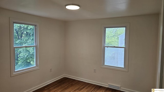 spare room with baseboards, healthy amount of natural light, and dark wood finished floors