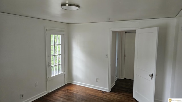 unfurnished room with dark wood-type flooring and baseboards