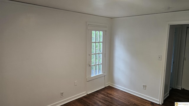 spare room with dark wood-style flooring, baseboards, and ornamental molding