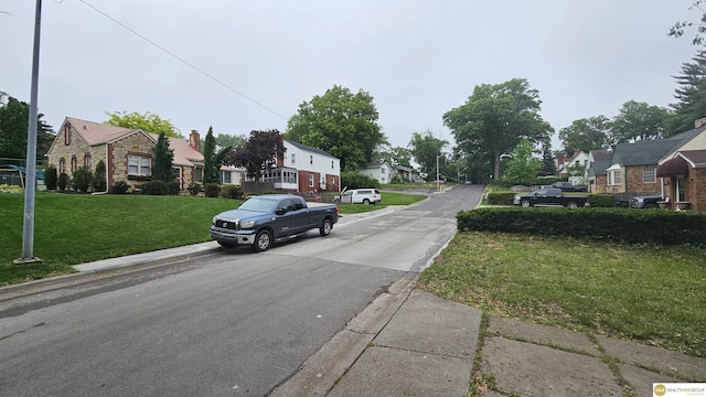 view of asphalt road with a residential view and curbs