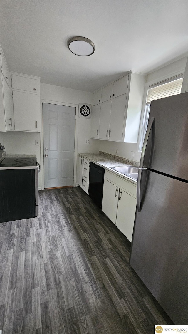 kitchen featuring appliances with stainless steel finishes, a sink, dark wood finished floors, light countertops, and white cabinetry
