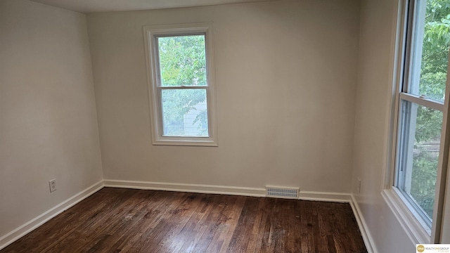 unfurnished room with healthy amount of natural light and dark wood-type flooring