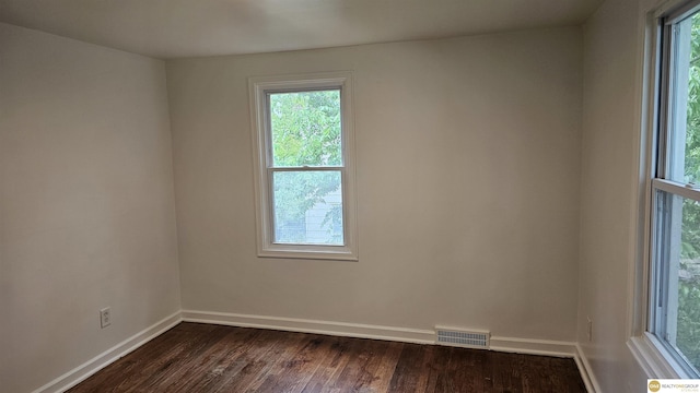empty room with plenty of natural light, dark wood finished floors, and baseboards