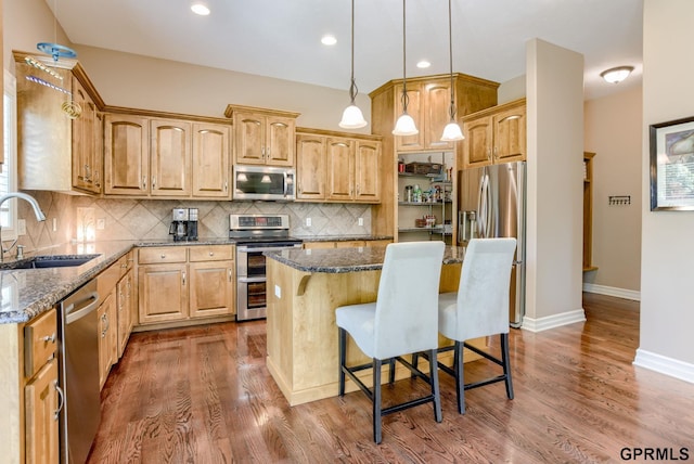 7320 S 169th St, Omaha, NE 68136 - kitchen featuring appliances with stainless steel finishes, a sink, dark stone counters, a kitchen island, and a kitchen bar