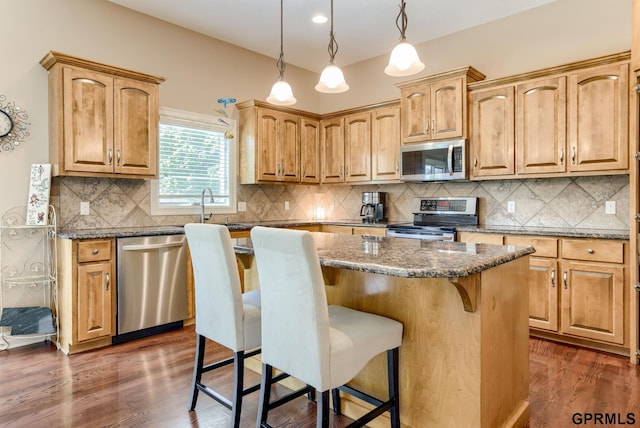 7320 S 169th St, Omaha, NE 68136 - kitchen featuring appliances with stainless steel finishes, a kitchen breakfast bar, a center island, dark stone counters, and tasteful backsplash