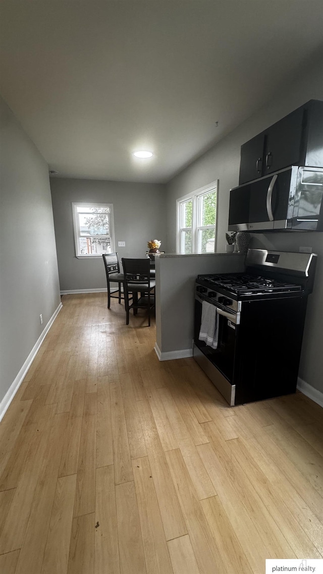 kitchen with appliances with stainless steel finishes, light wood-style floors, baseboards, and dark cabinets