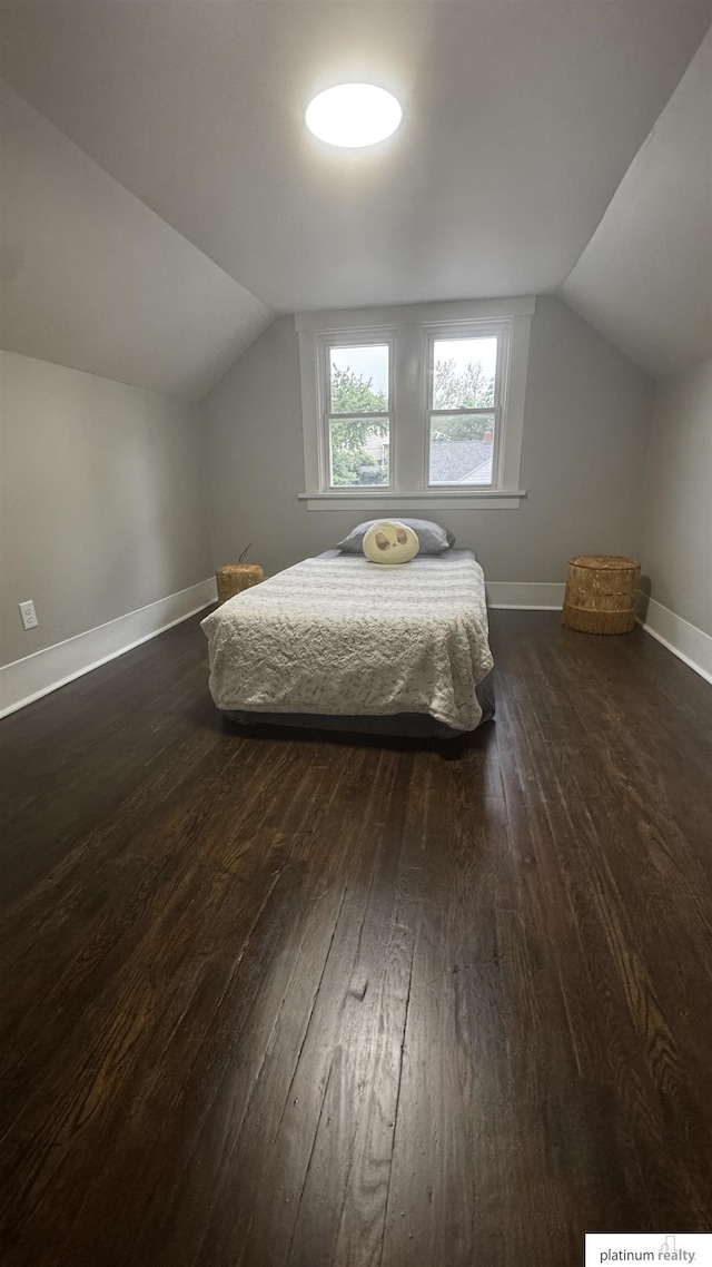 bedroom with vaulted ceiling, dark wood finished floors, and baseboards