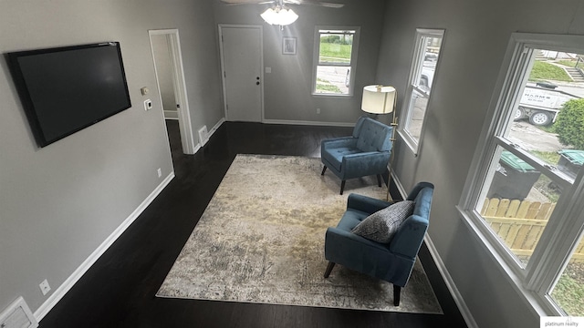 living area with dark wood-type flooring, baseboards, and ceiling fan