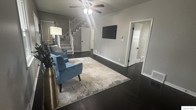 sitting room with a ceiling fan, stairway, baseboards, and dark wood-type flooring