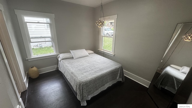bedroom with multiple windows, baseboards, and dark wood-type flooring