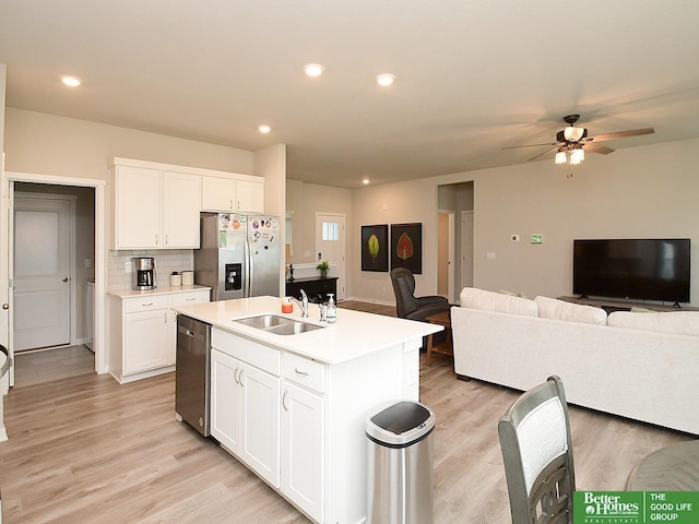 kitchen featuring appliances with stainless steel finishes, a sink, light wood finished floors, a ceiling fan, and open floor plan