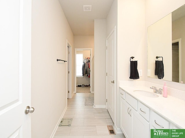 bathroom featuring vanity, baseboards, a spacious closet, and tile patterned flooring