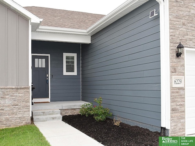 view of exterior entry with roof with shingles