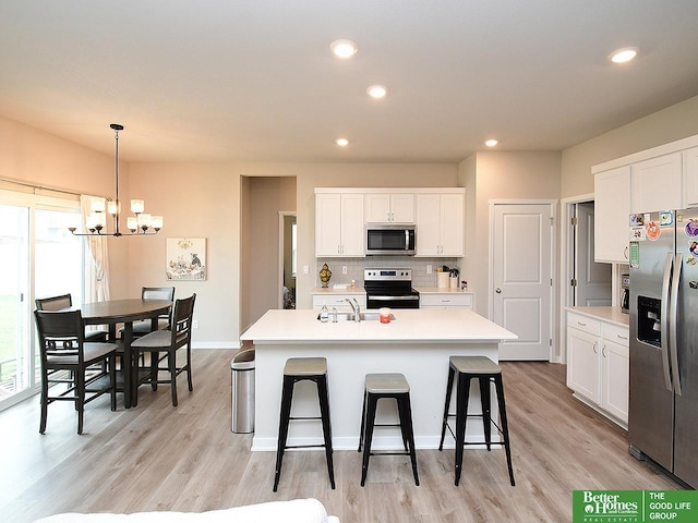 kitchen with stainless steel appliances, a sink, a chandelier, a kitchen bar, and tasteful backsplash
