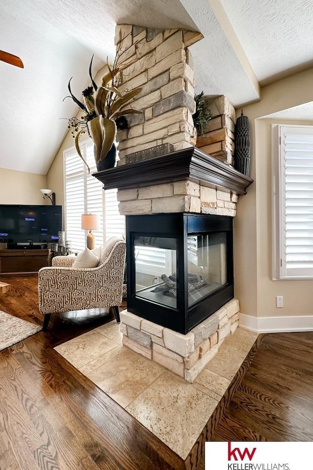 7815 Maui Cir, Papillion, NE 68046 - detailed view of a textured ceiling, a stone fireplace, wood finished floors, and baseboards