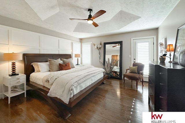 7815 Maui Cir, Papillion, NE 68046 - bedroom featuring a textured ceiling, multiple windows, dark wood finished floors, a raised ceiling, and a decorative wall
