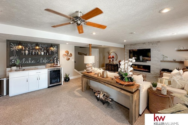 7815 Maui Cir, Papillion, NE 68046 - living room featuring beverage cooler, bar with sink, a fireplace, a textured ceiling, and light carpet
