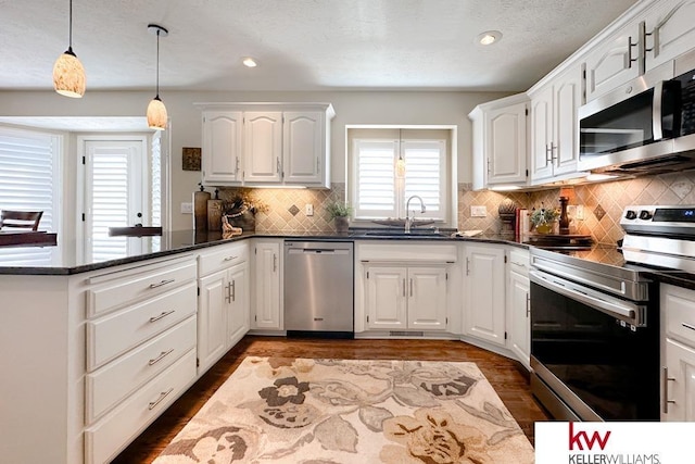 7815 Maui Cir, Papillion, NE 68046 - kitchen with stainless steel appliances, a sink, a peninsula, dark wood finished floors, and white cabinetry