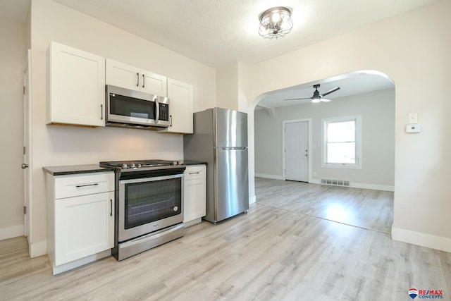 3021 N St, Lincoln, NE 68510 - kitchen with stainless steel appliances, arched walkways, dark countertops, light wood-style flooring, and ceiling fan
