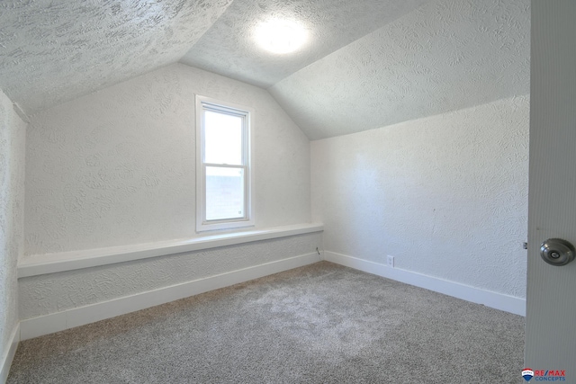 3021 N St, Lincoln, NE 68510 - additional living space with a textured wall, a textured ceiling, vaulted ceiling, baseboards, and carpet floors