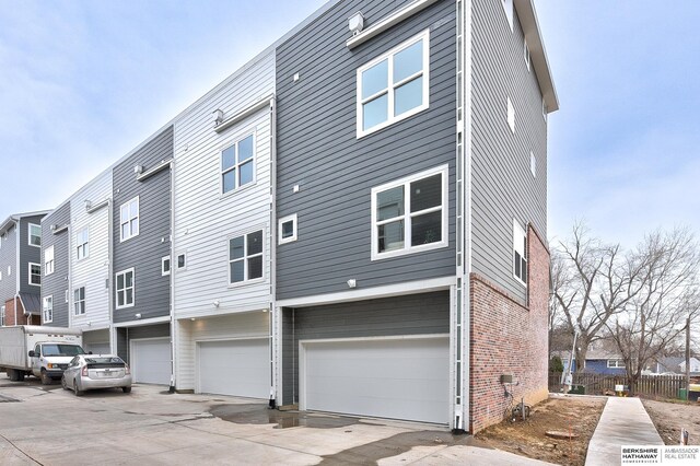 1917 Dahlman Rows Plz, Omaha, NE 68108 - back of house featuring a garage, brick siding, and driveway