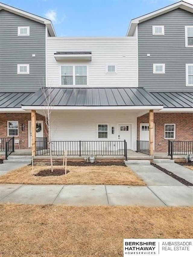 1921 Dahlman Rows Plz, Omaha, NE 68108 - view of property with a porch, brick siding, and metal roof