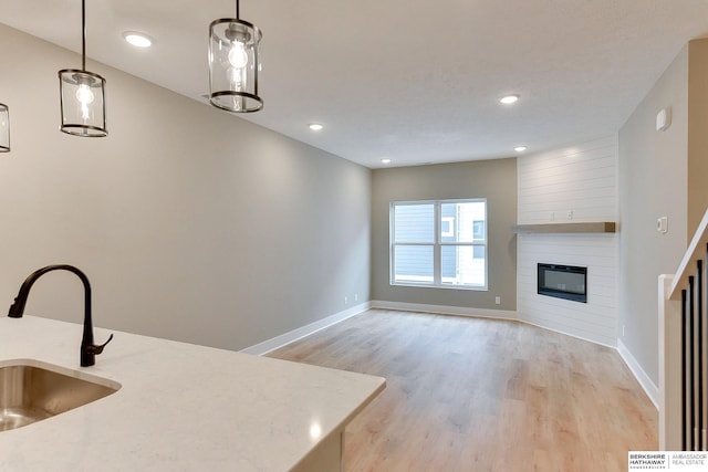 1921 Dahlman Rows Plz, Omaha, NE 68108 - kitchen featuring a sink, light wood-type flooring, baseboards, a large fireplace, and recessed lighting