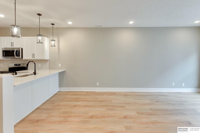 1921 Dahlman Rows Plz, Omaha, NE 68108 - kitchen with appliances with stainless steel finishes, a sink, backsplash, white cabinets, and light wood-type flooring