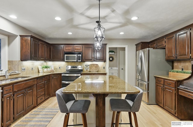 16712 V St, Omaha, NE 68135 - kitchen featuring appliances with stainless steel finishes, a sink, light wood finished floors, a kitchen island, and recessed lighting
