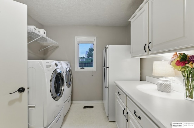 16712 V St, Omaha, NE 68135 - laundry area featuring baseboards, separate washer and dryer, a textured ceiling, cabinet space, and light flooring