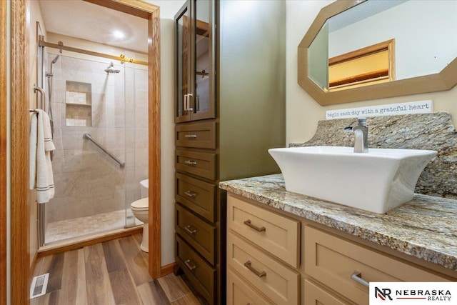 650 Heatherwood Dr, Fremont, NE 68025 - bathroom featuring toilet, a stall shower, wood finished floors, and vanity