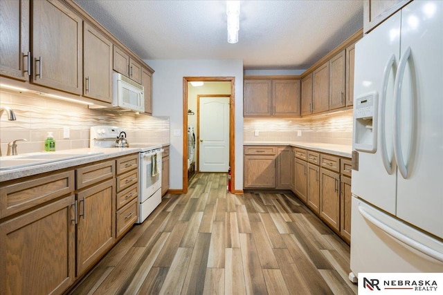 650 Heatherwood Dr, Fremont, NE 68025 - kitchen with white appliances, wood finished floors, tasteful backsplash, light countertops, and a textured ceiling